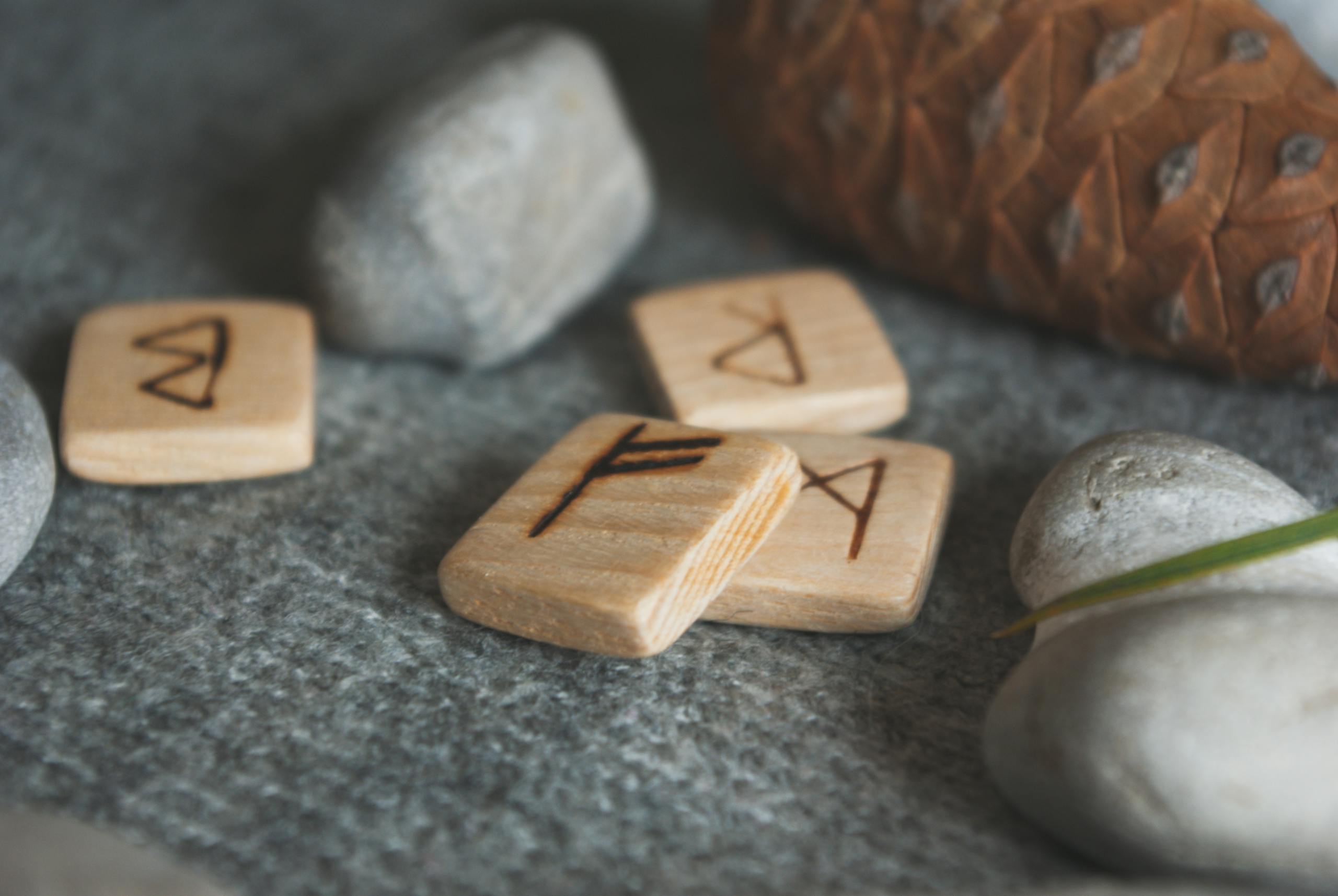 Wooden runes and stones on a warm, cozy fabric background, evoking mystical Scandinavian vibes.